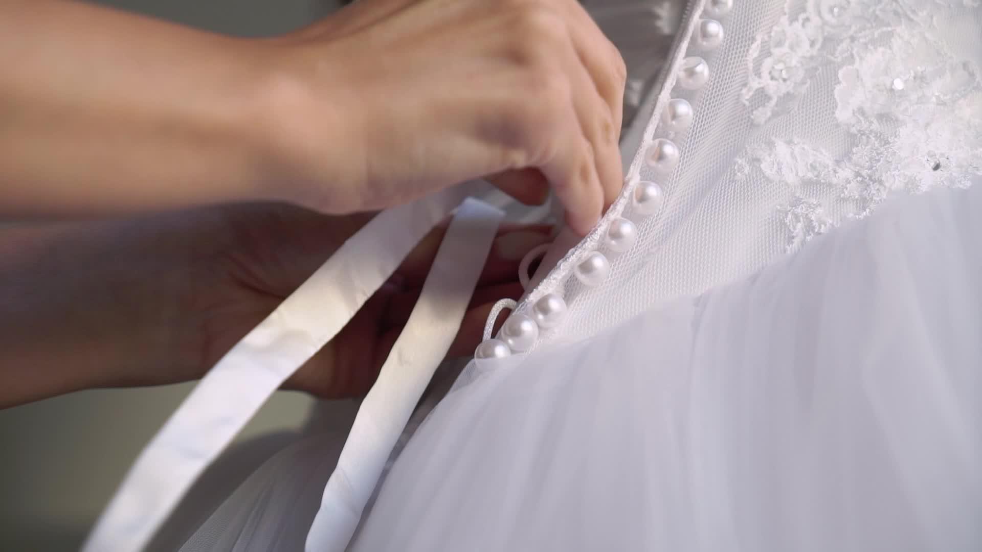 帮助年轻新娘穿上婚纱的伴娘视频的预览图