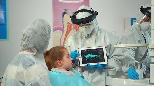 在数字屏幕上指向母亲解释x光时使用牙科医生的西装视频的预览图