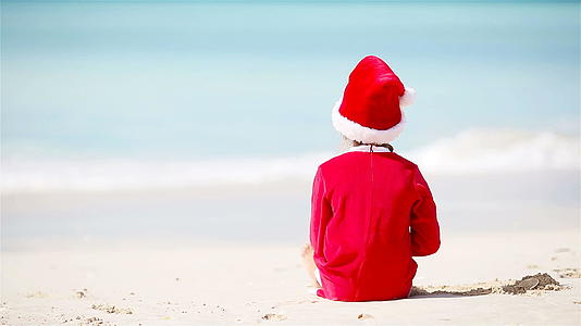 圣诞节期间在白色海滩上戴圣诞帽的小女孩视频的预览图