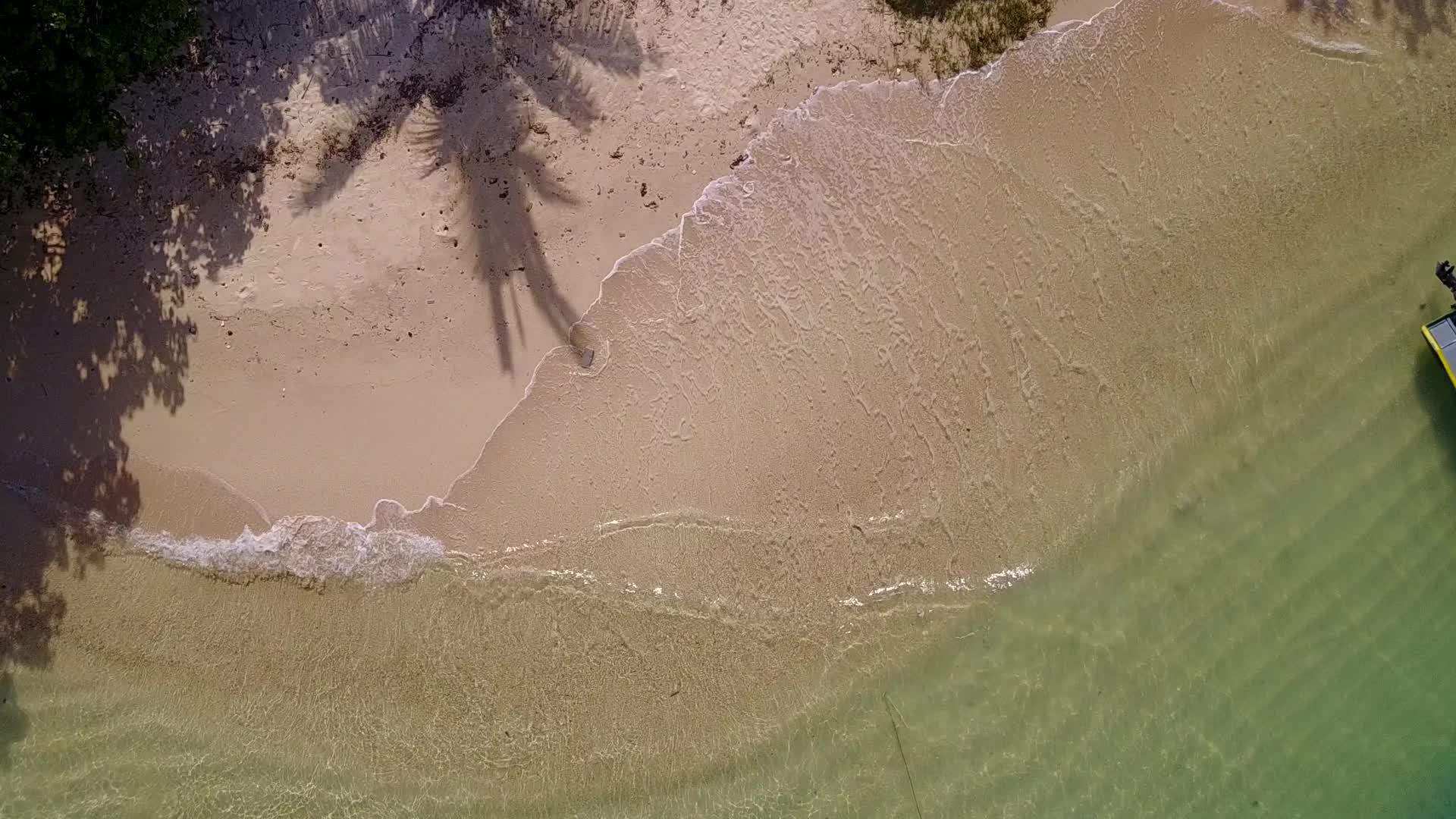 日出后以白沙为背景的完美海岸海滩在蓝色海洋中航行视频的预览图