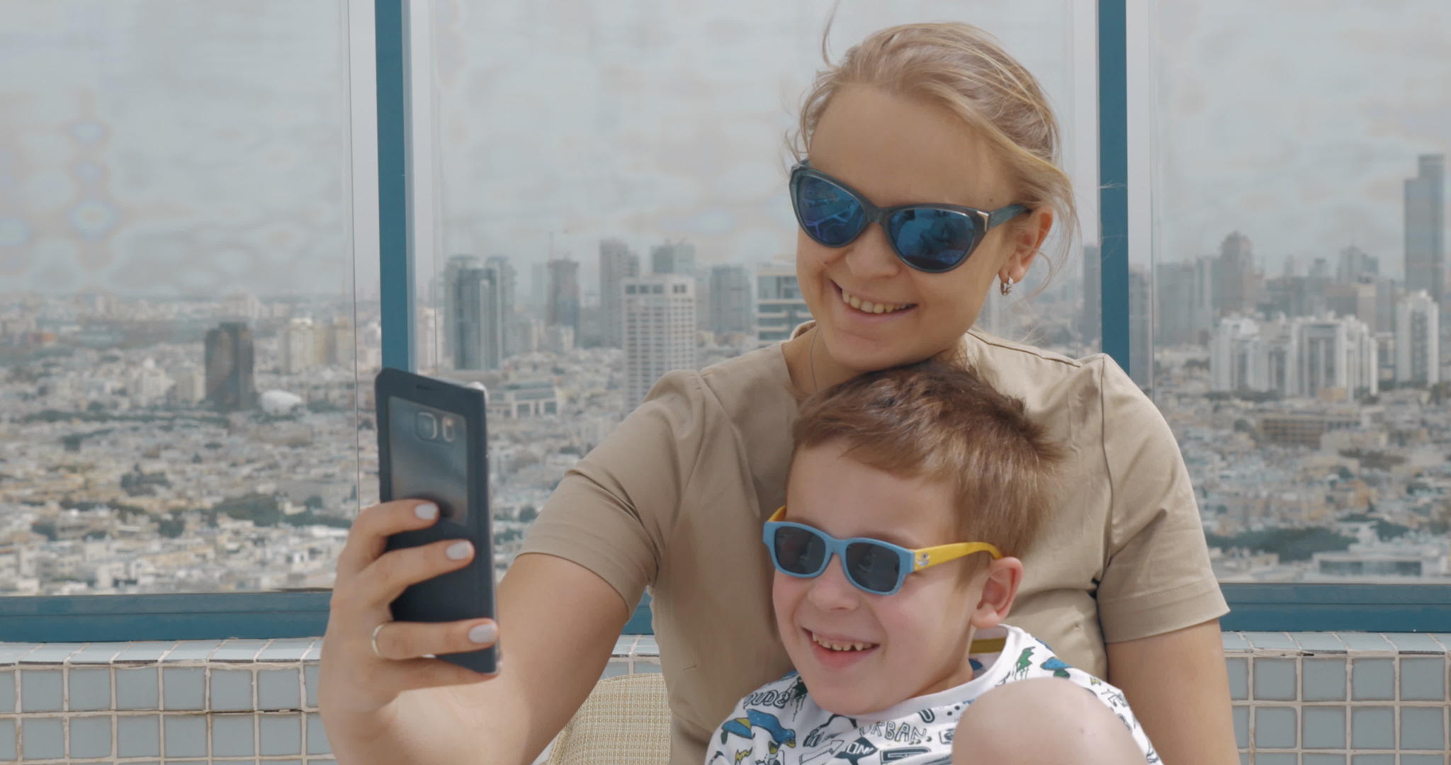 母亲和孩子在酒店屋顶上用手机自拍电话Aviv视频的预览图