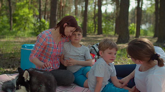 在夏季家庭露营期间两位母亲、两个儿子和西伯利亚哈士奇视频的预览图