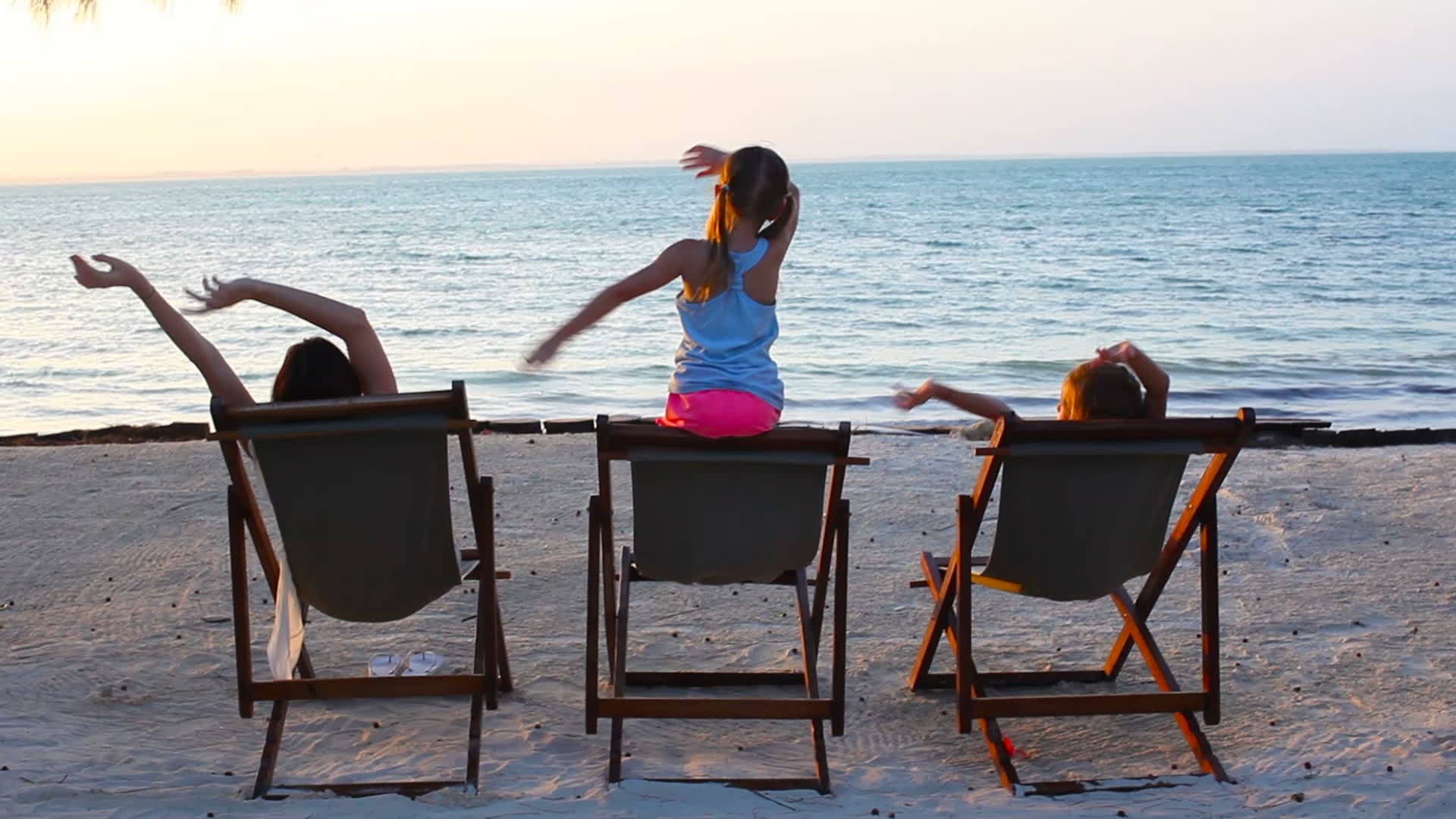 日落时女孩和妈妈坐在沙滩椅上视频的预览图