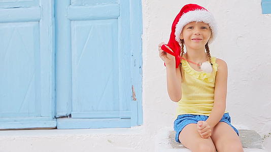 圣诞节期间米科诺斯岛老街上戴着圣诞帽的小女孩在户外视频的预览图