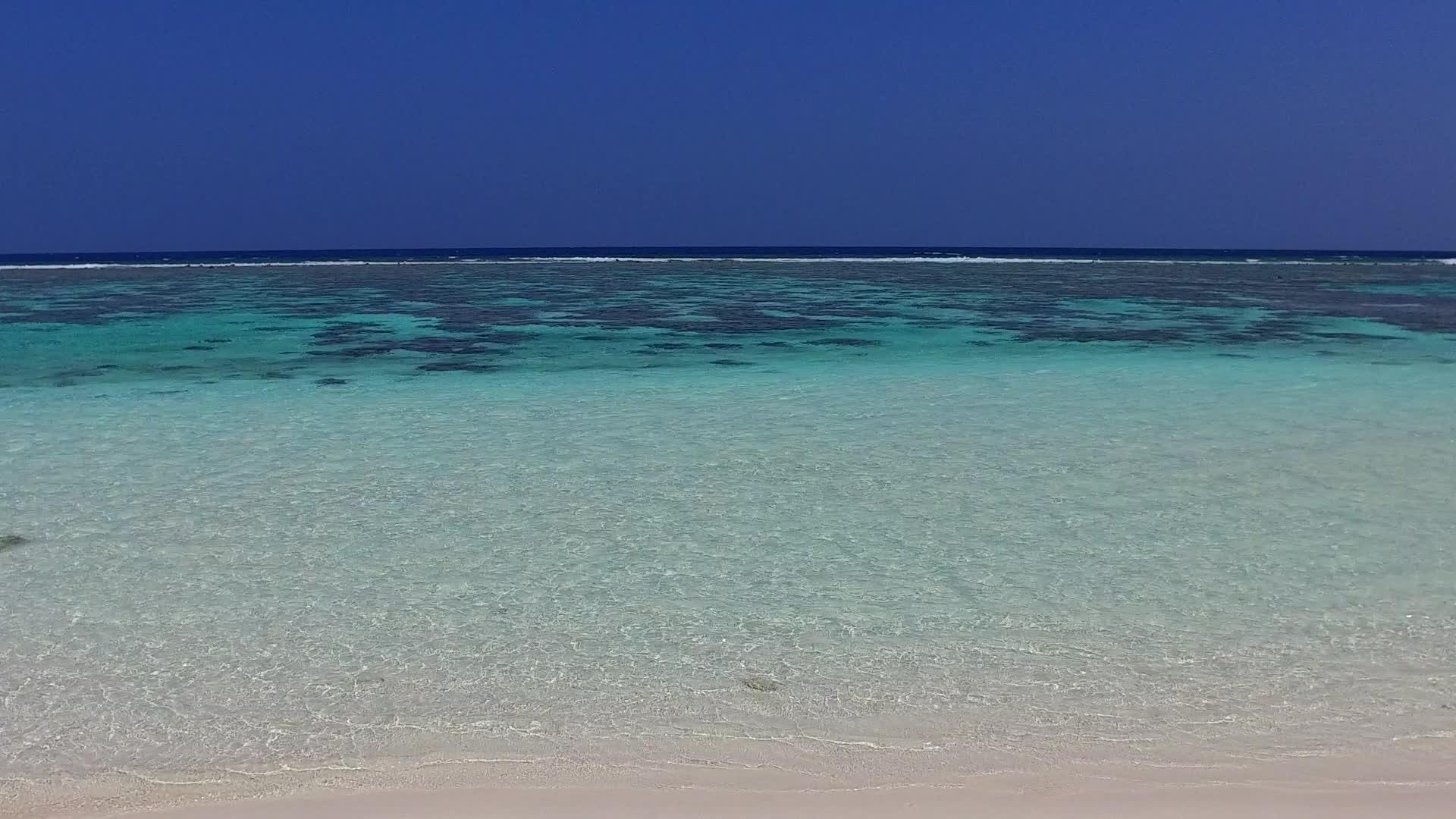 蓝色的环礁湖在蓝色的海滩上海浪附近有白色的沙视频的预览图