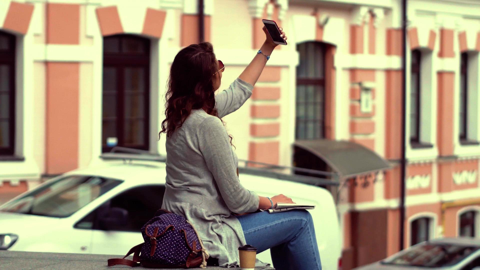 年轻的观光女青年坐在栏杆上自拍视频的预览图