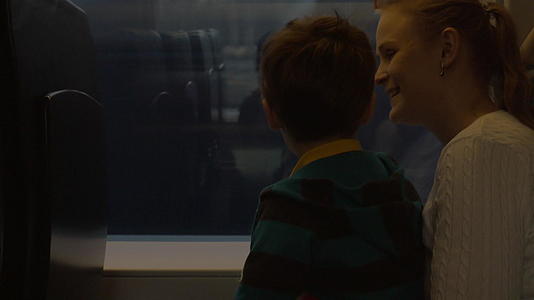 小男孩和他的母亲坐在铁路火车的窗口看着货车视频的预览图