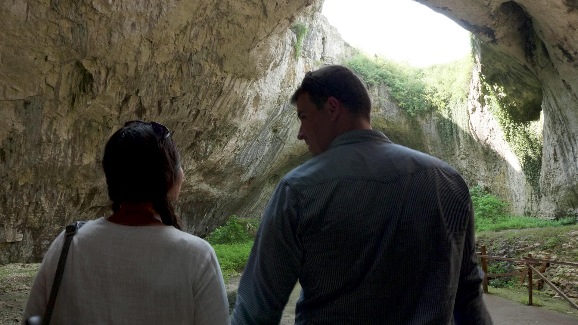 一对夫妇走在山上探索一个大洞穴视频的预览图