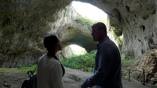 一对夫妇看着山上的一个大洞穴视频的预览图