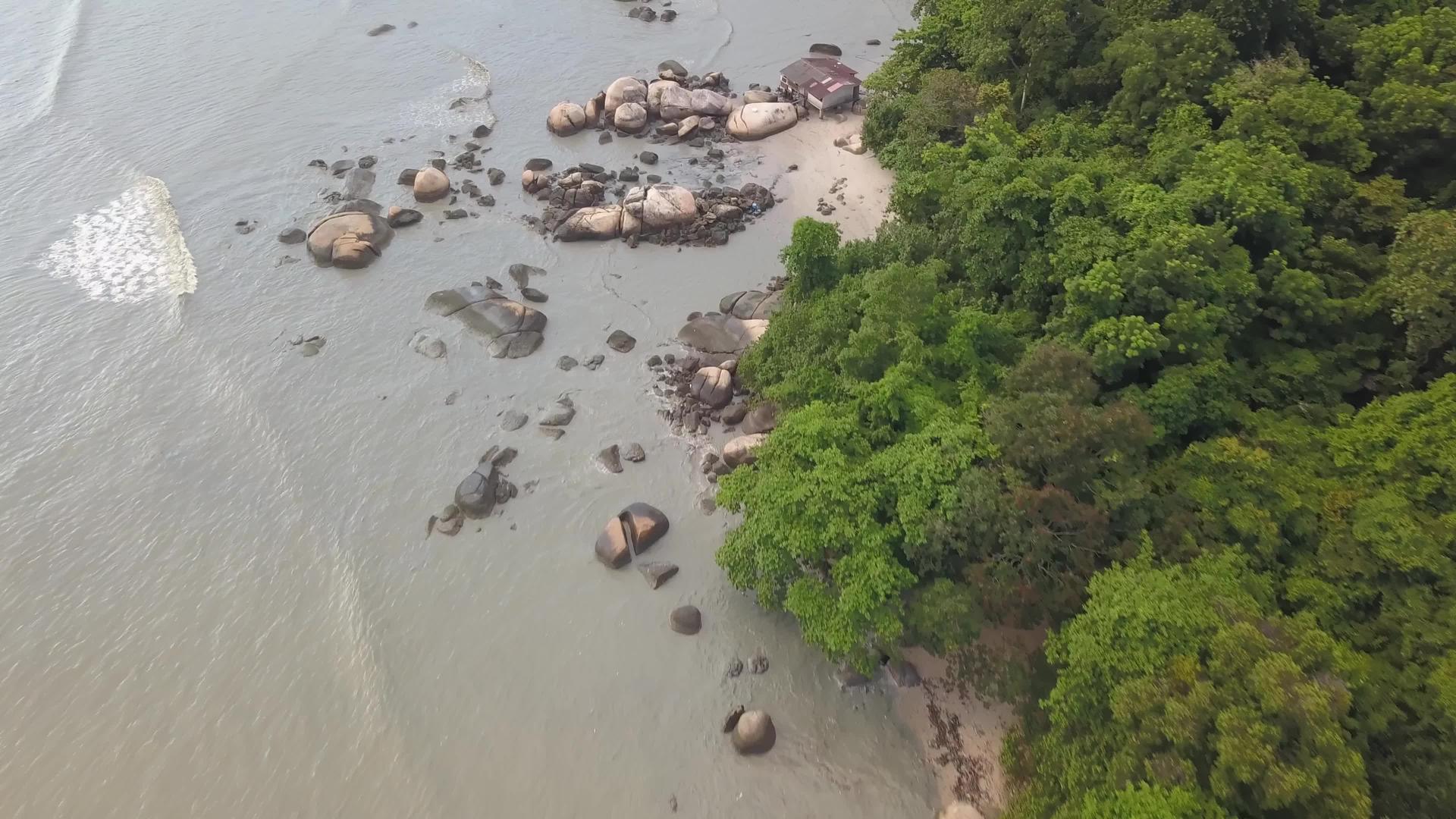 在绿林旁边的沿海岩石上飞行视频的预览图