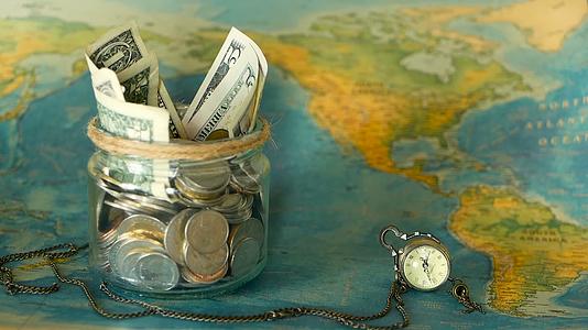 在世界地图背景的玻璃罐中旅行预算的概念是为假期省钱视频的预览图
