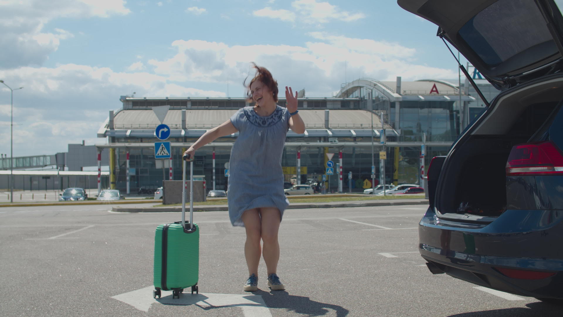年轻快乐的女人独自带着手提箱在机场大楼附近跳舞视频的预览图