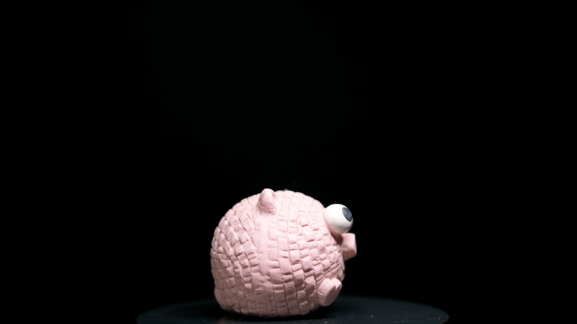 粉色橡皮猪玩具在黑色背景上旋转视频的预览图