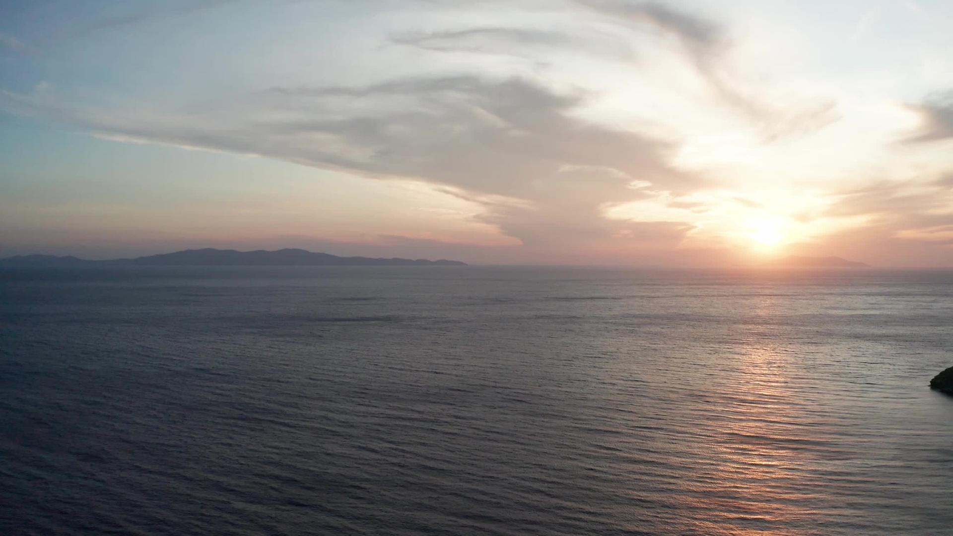 空中无人驾驶飞机环视着海平面上美丽的日落视频的预览图