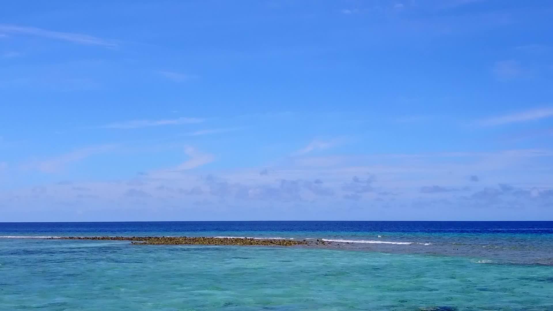 海滨海滩度假村从白色沙滩底部的绿色海流出视频的预览图