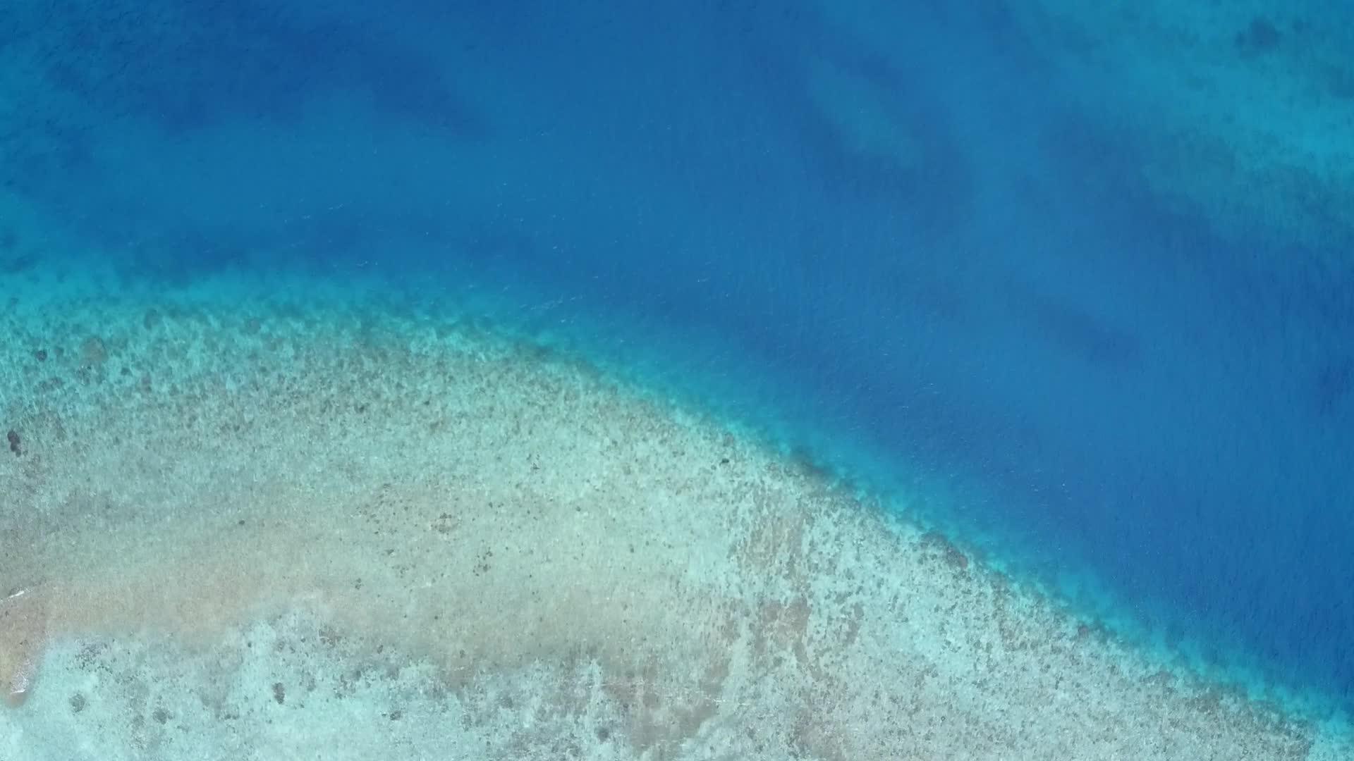 以白色沙子为背景的深蓝色水域为代表的异国情调的环礁湖海滩假日空中视频的预览图