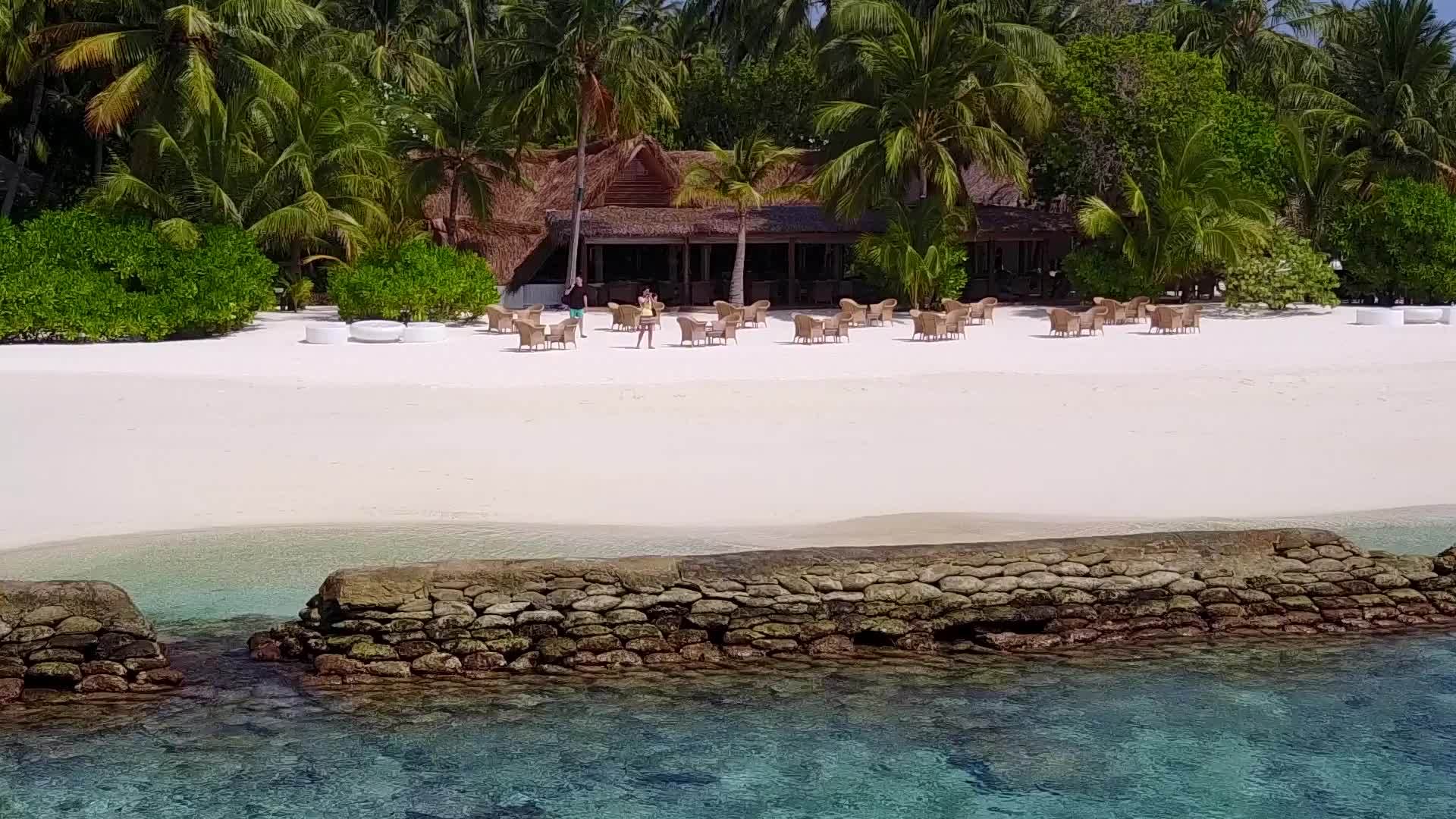 海滨海滩休息场景以水蓝色环礁湖和白色沙底为背景视频的预览图