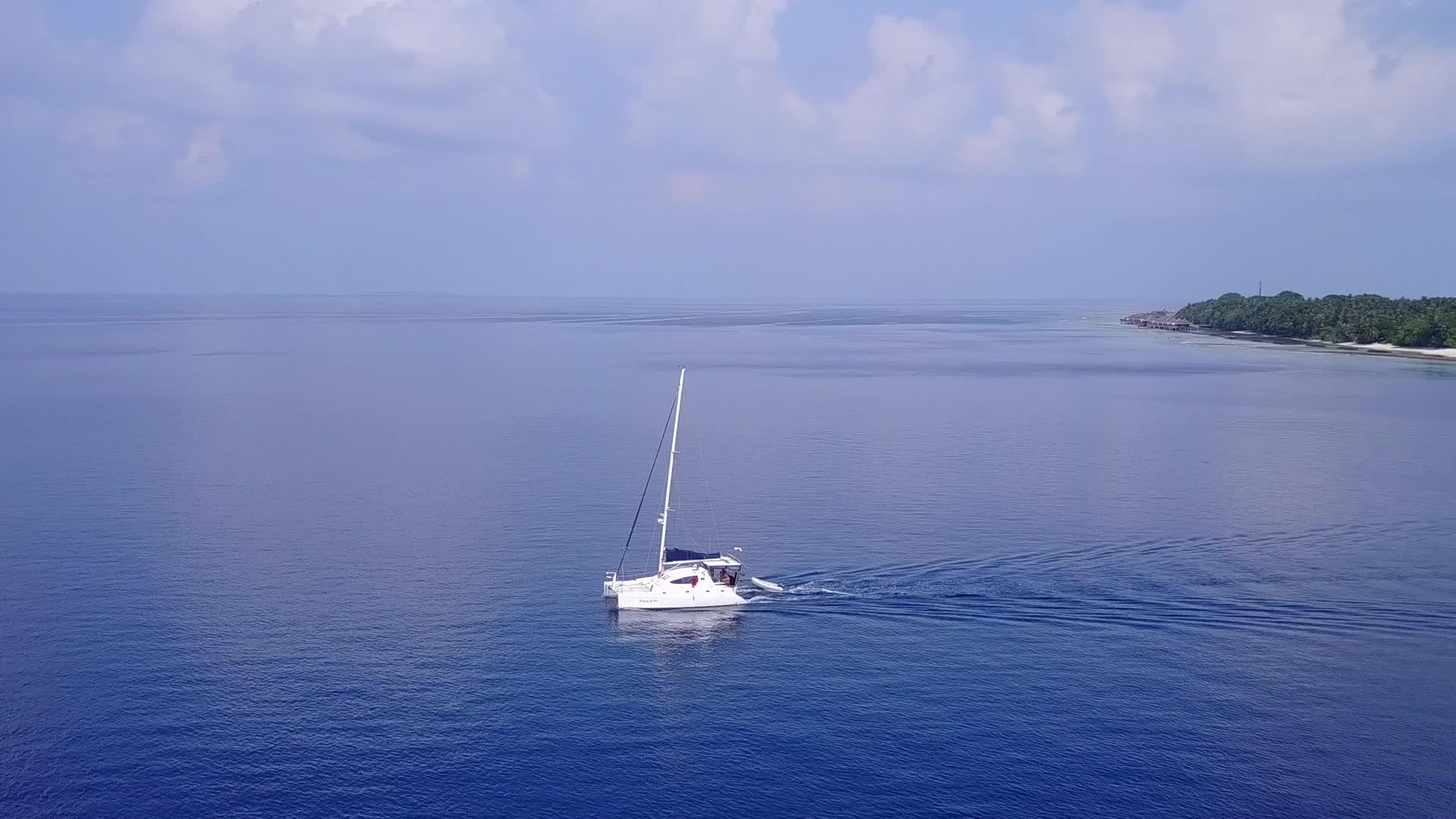 蓝色的海洋和干净的沙质背景下的海岸海滩度假无人机视频的预览图