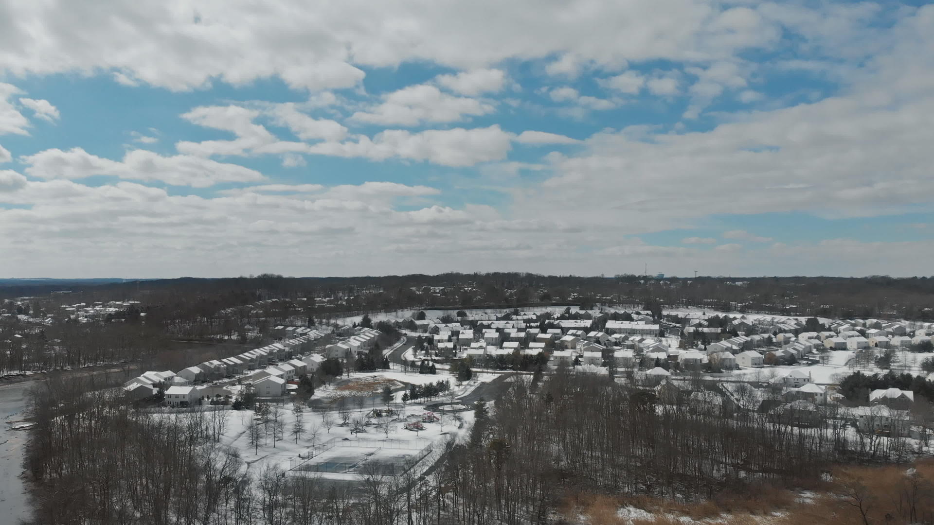 无人驾驶飞机的视频飞越了小镇附近的树木上面覆盖着积雪的屋顶视频的预览图