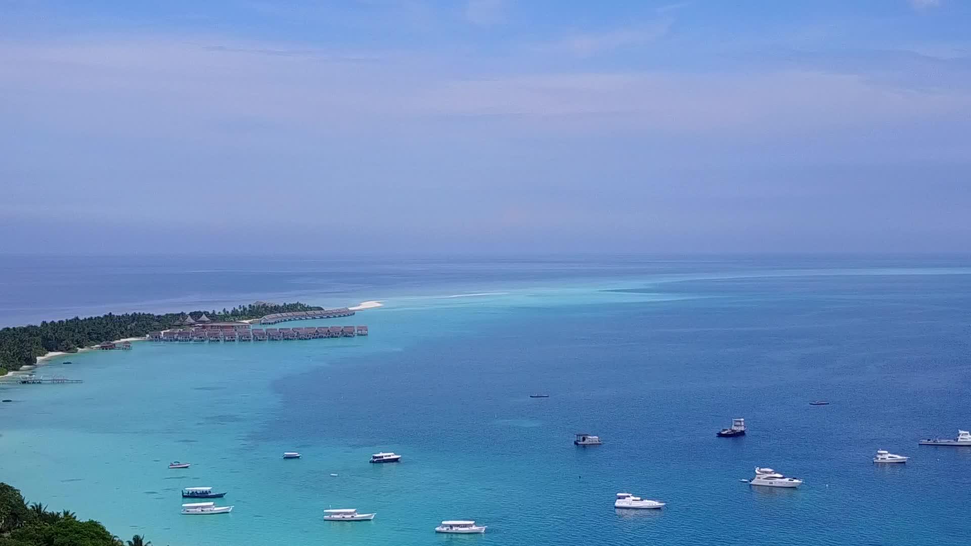 在蓝色泻湖和亮沙的背景下无人机在宁静的度假海滩上空中旅行视频的预览图