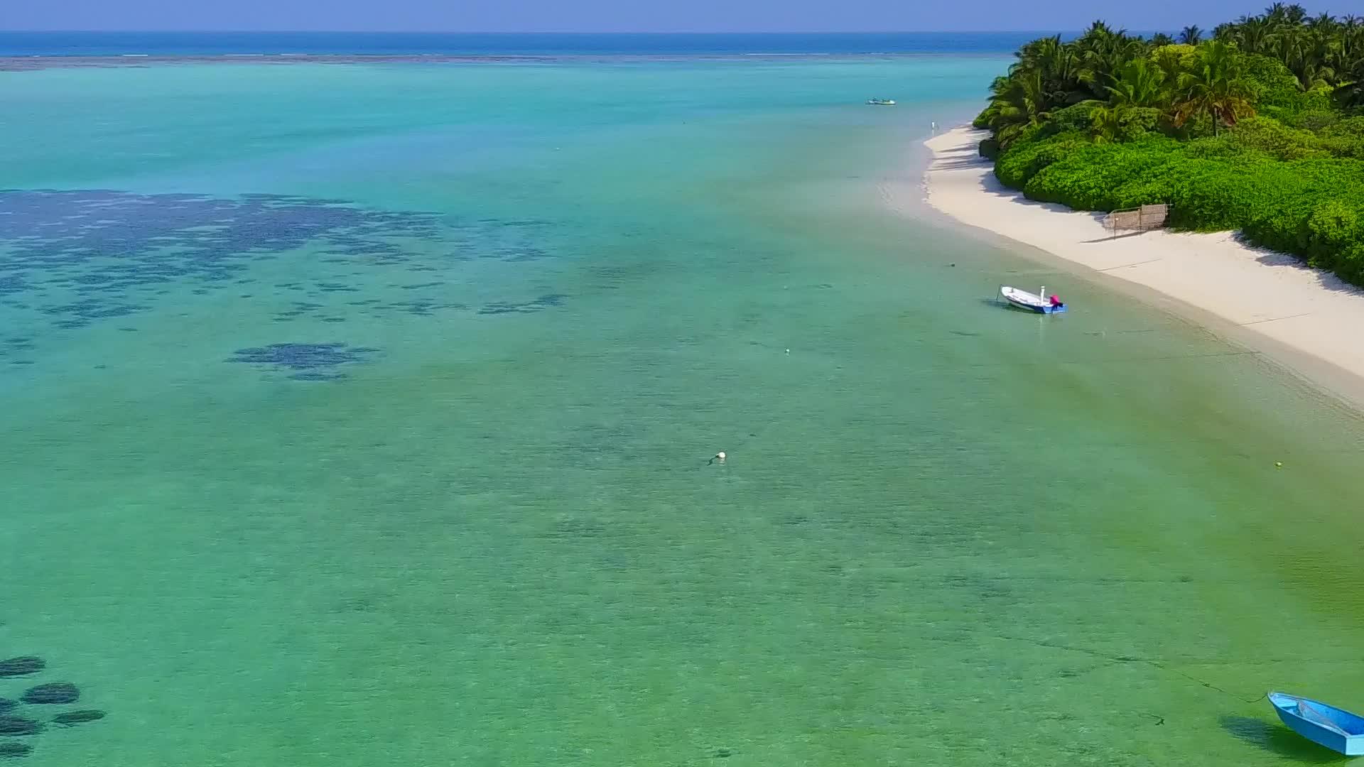 蓝色环礁湖和明亮的蓝色沙滩背景下美丽的海岸线海滩生活方式视频的预览图
