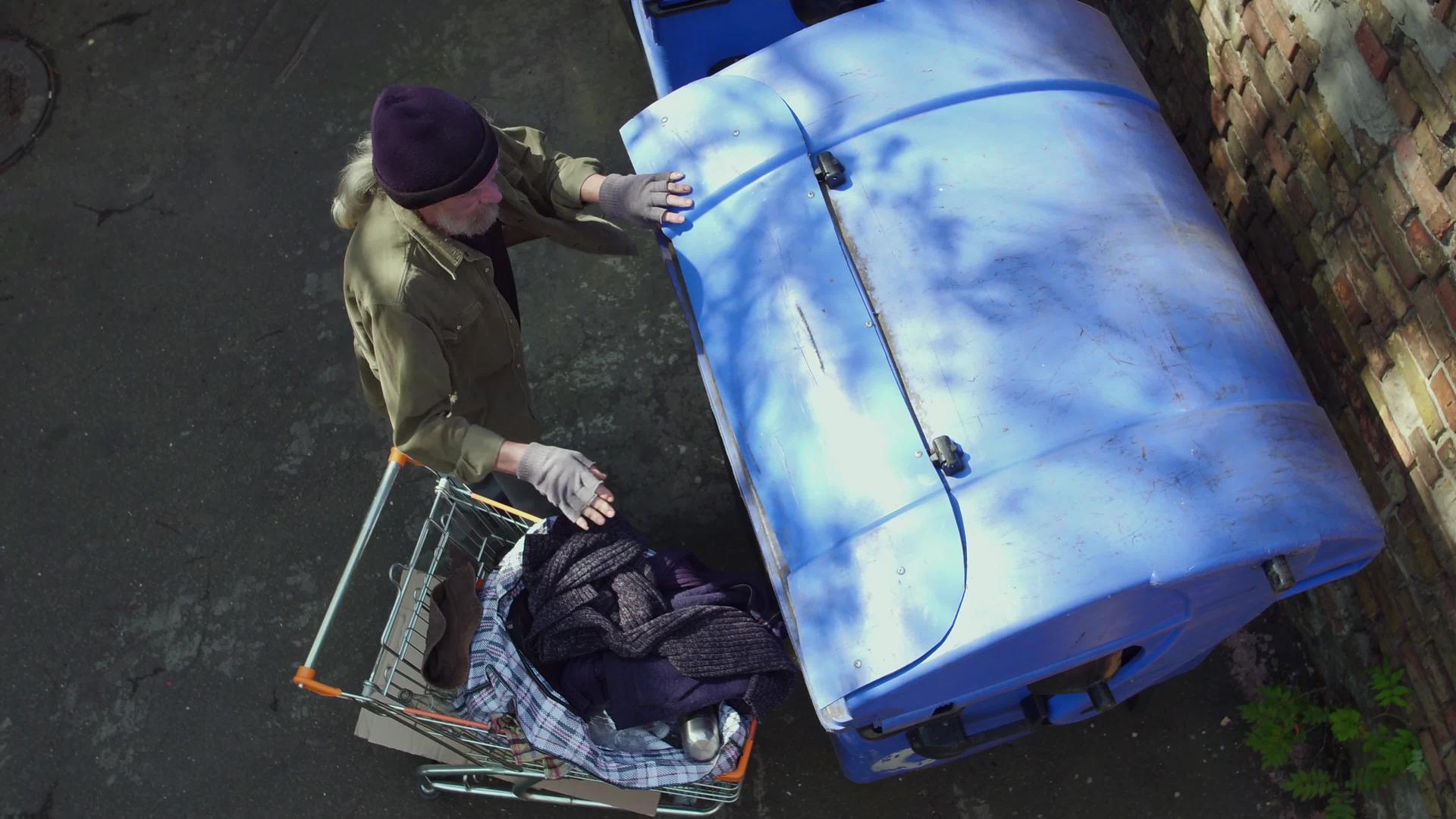 无家可归的人使用购物车接近垃圾桶其风景最高视频的预览图