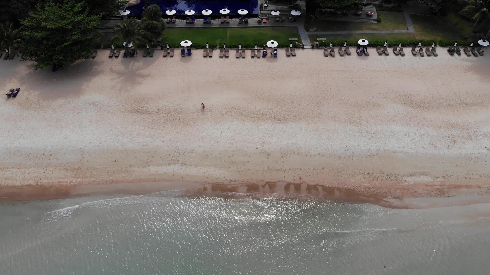 海滩上有许多配对的遮阳休息者他们在荒凉的海滩上使用雨伞和清洁视频的预览图