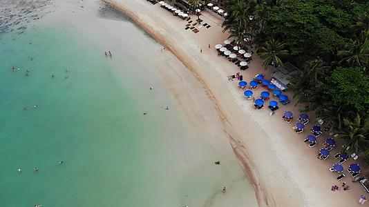海滩上有许多配对的遮阳休息者他们在荒凉的海滩上使用雨伞和清洁视频的预览图