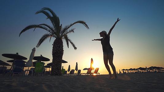 女强自信的女士张开双臂在日出时用棕榈树圆背旋转视频的预览图