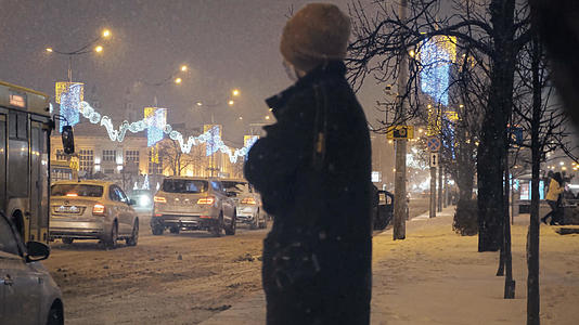 冬天下雪的夜晚在路边等待公交车的乘客视频的预览图