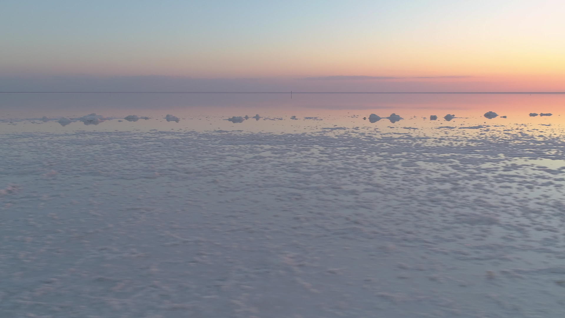 低角在盐湖上向右飞在五颜六色的日落时带着盐块视频的预览图