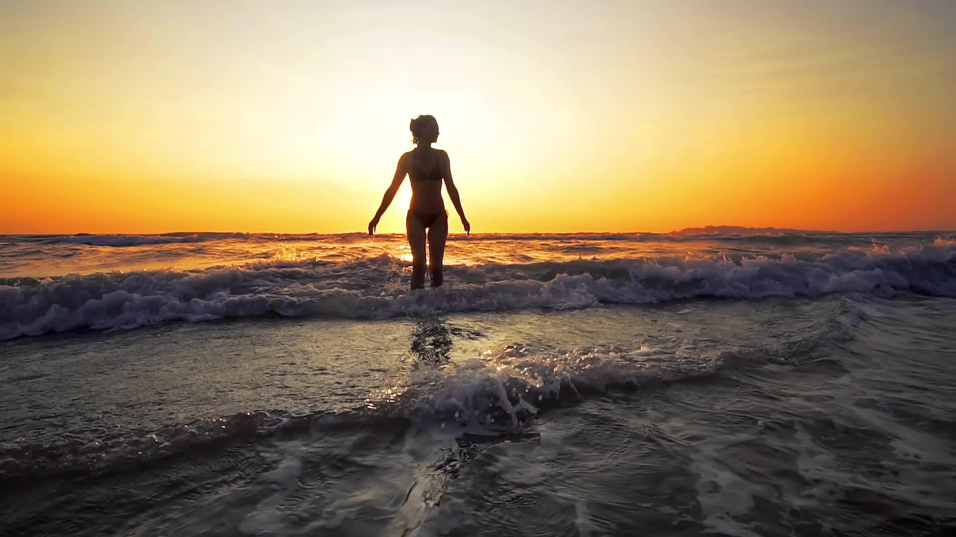 在海边的日出下女人张开双臂慢慢移动视频的预览图