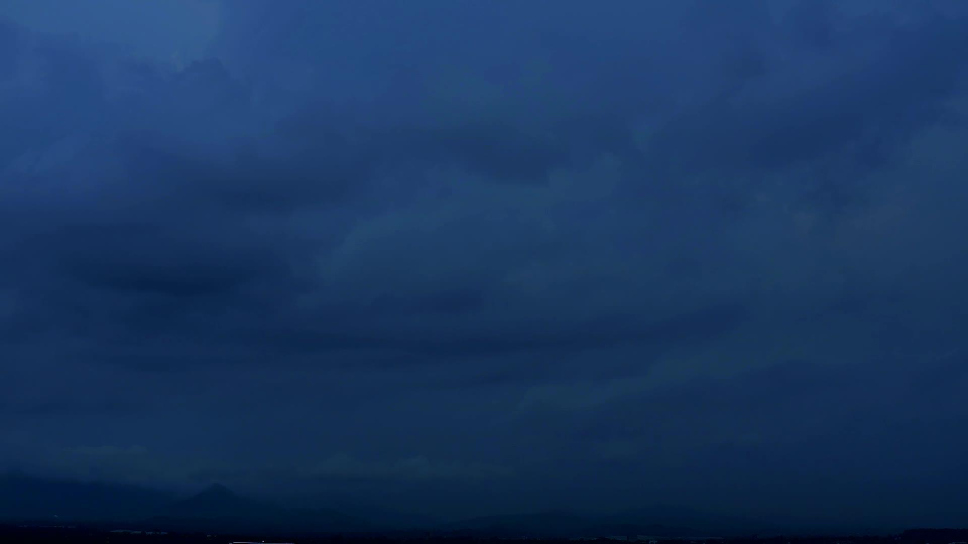 在黑暗的夜空中乌云飘过绿色的山顶视频的预览图