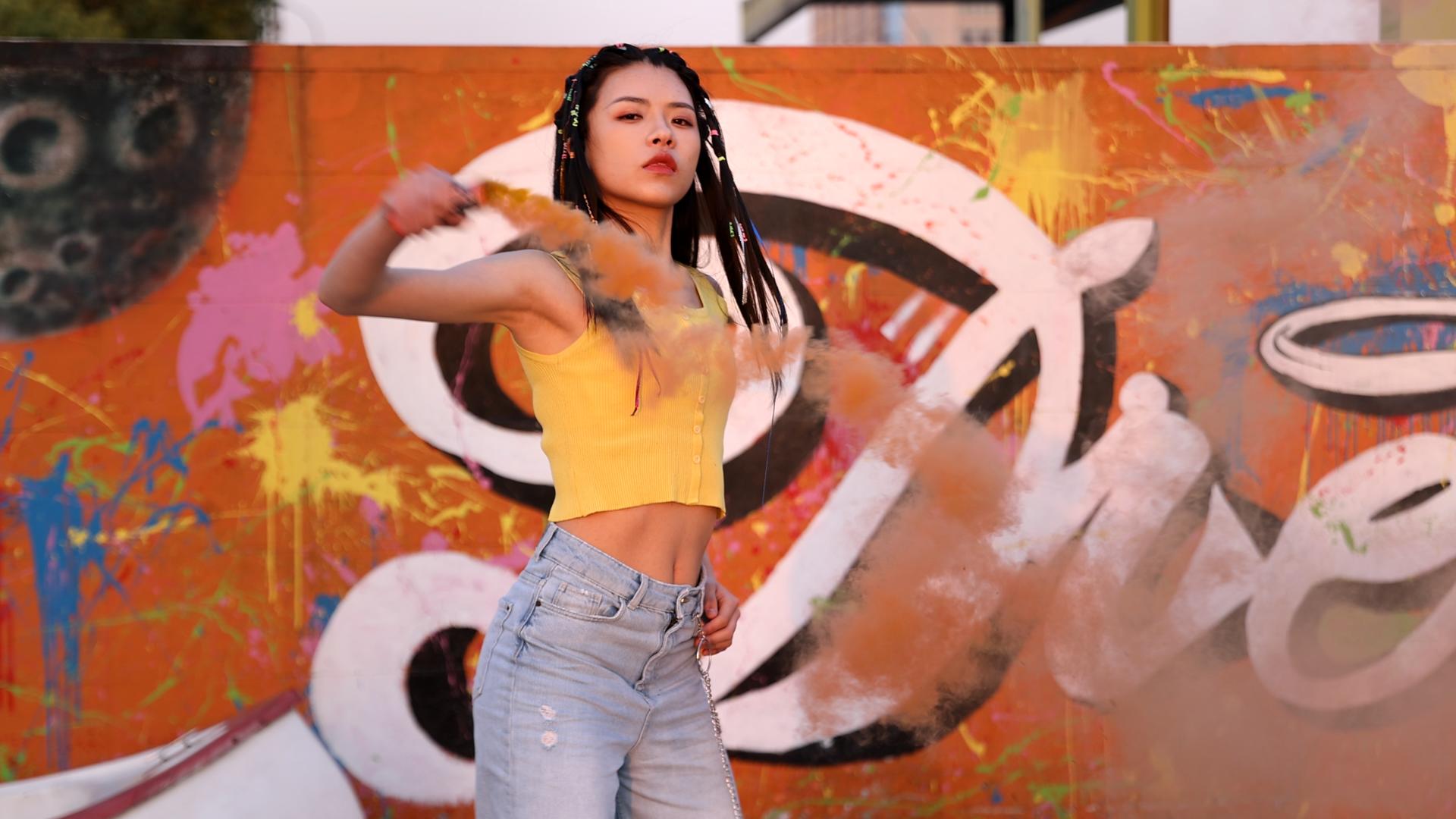 4K潮流嘻哈女孩涂鸦墙下挥动烟雾棒劲舞视频的预览图