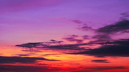 黑暗的紫色日落天空和阳光照亮了太阳和月光下的橙色云彩视频的预览图