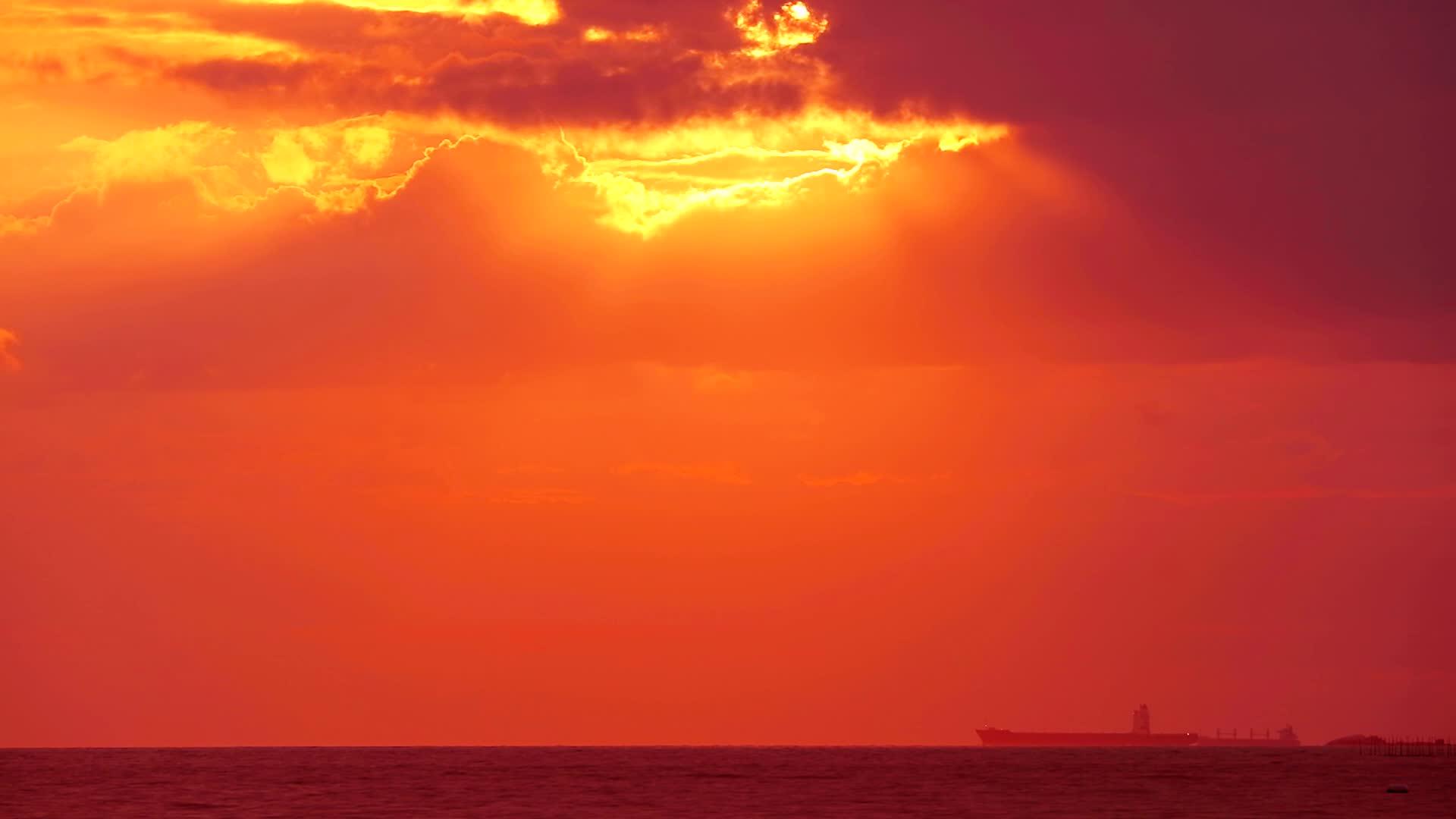 红色的阳光和反射光照在太阳的周围黑云在海面上落下视频的预览图
