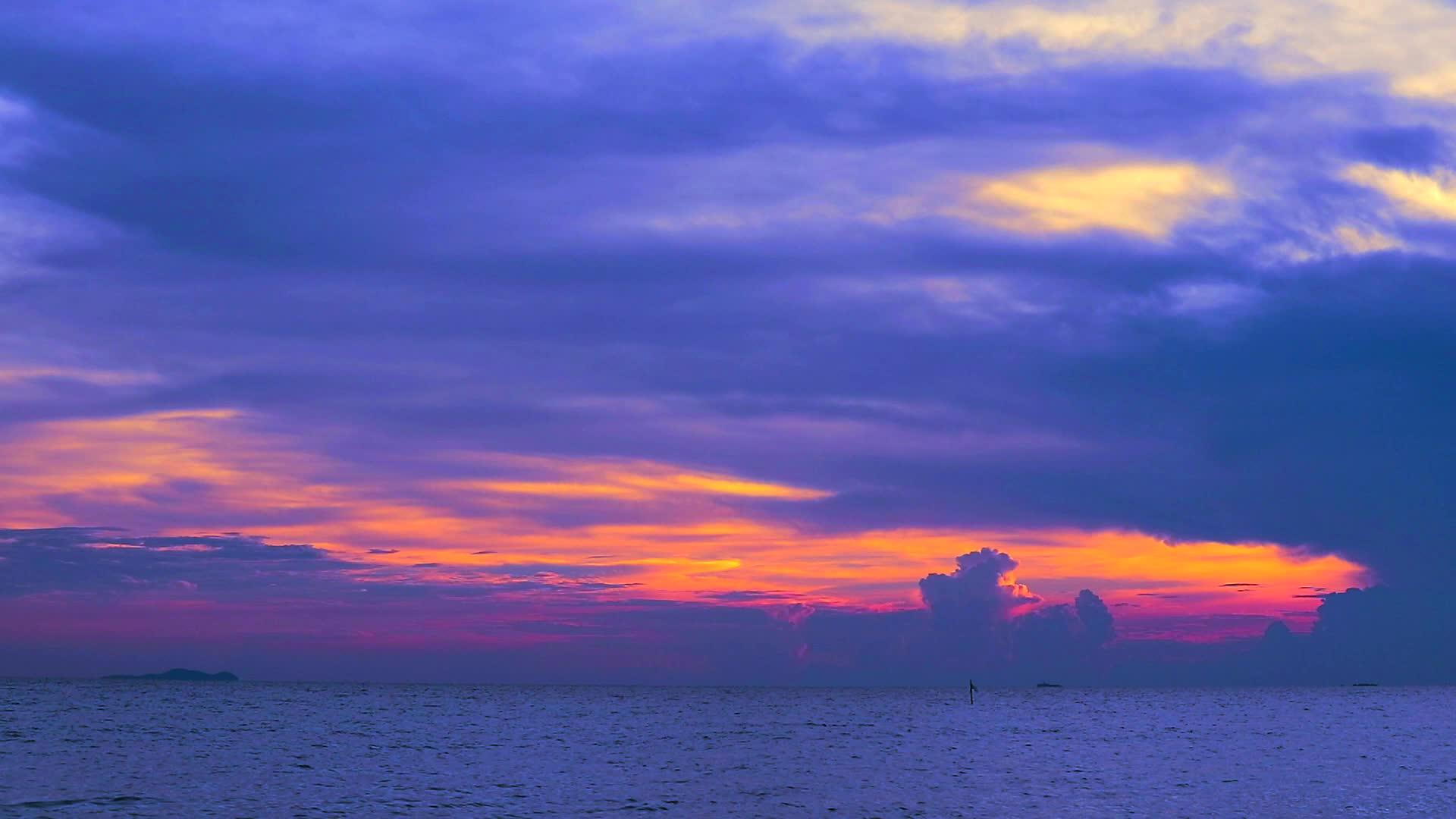 紫色的红色日落黑暗的红色天空和云朵在海面上飘动视频的预览图