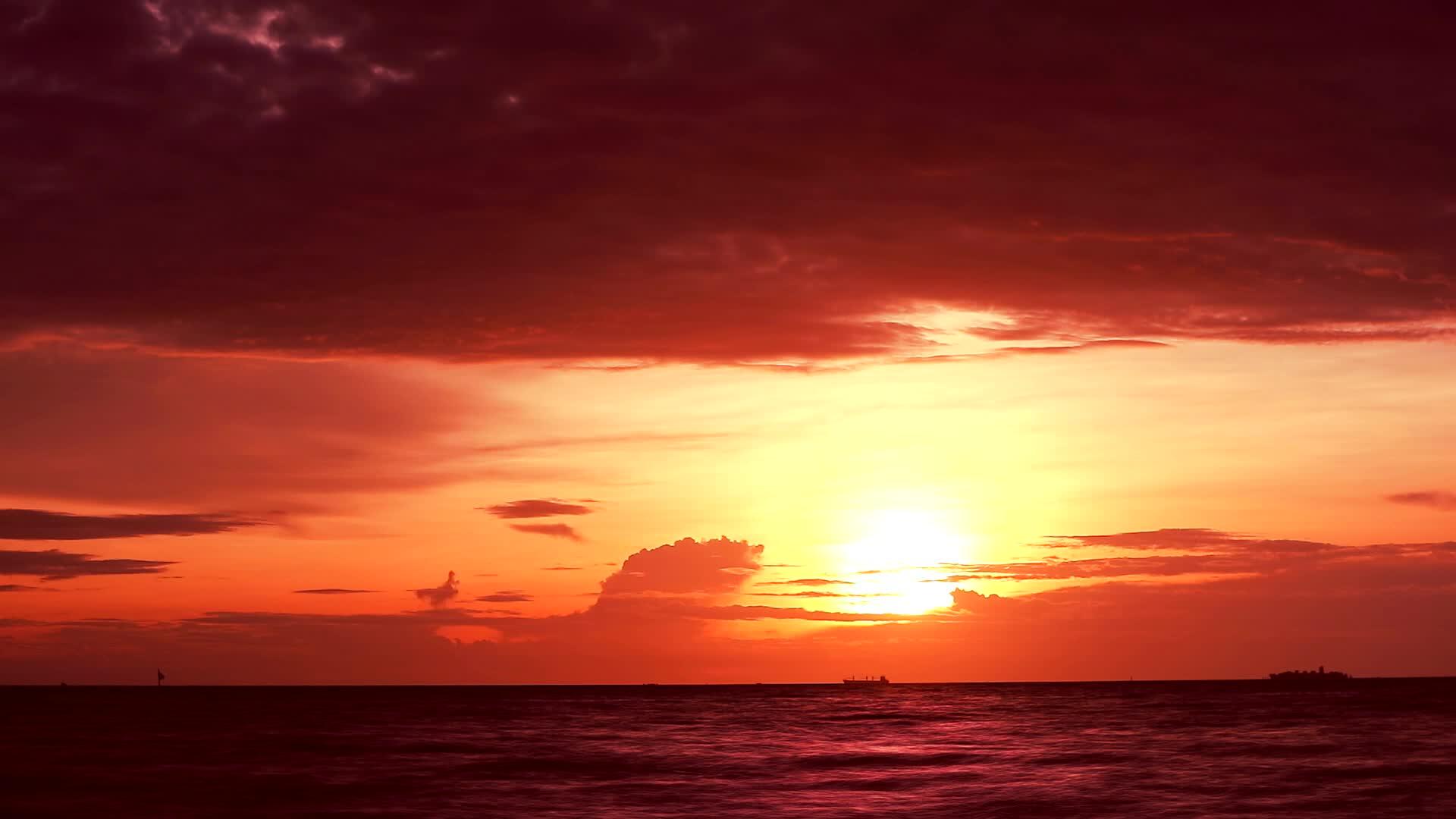 红色的太阳橙色的天空和深红的云在海上飘扬视频的预览图