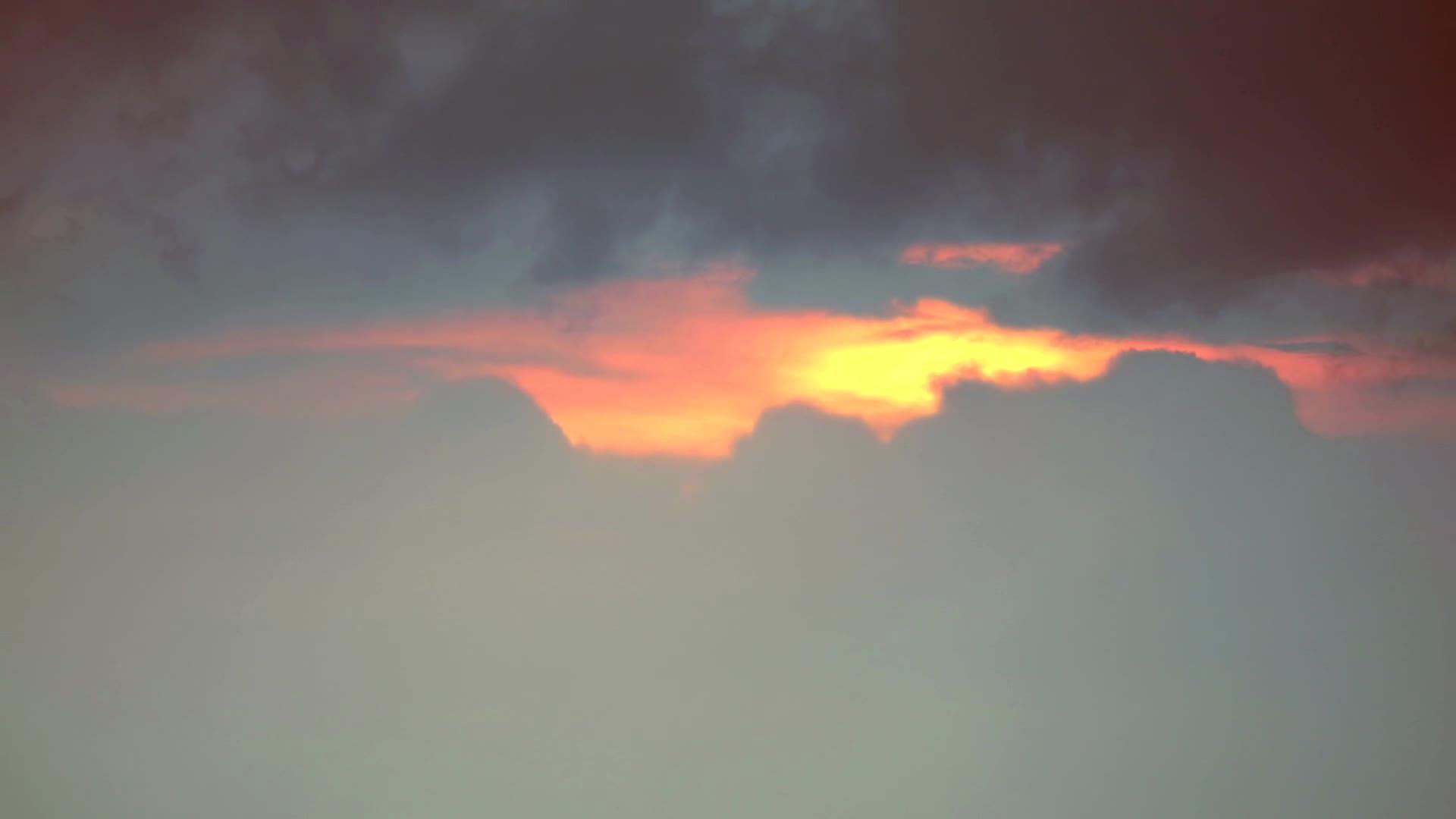 在灰色的乌云下日落通过橙色的天空背景移动视频的预览图