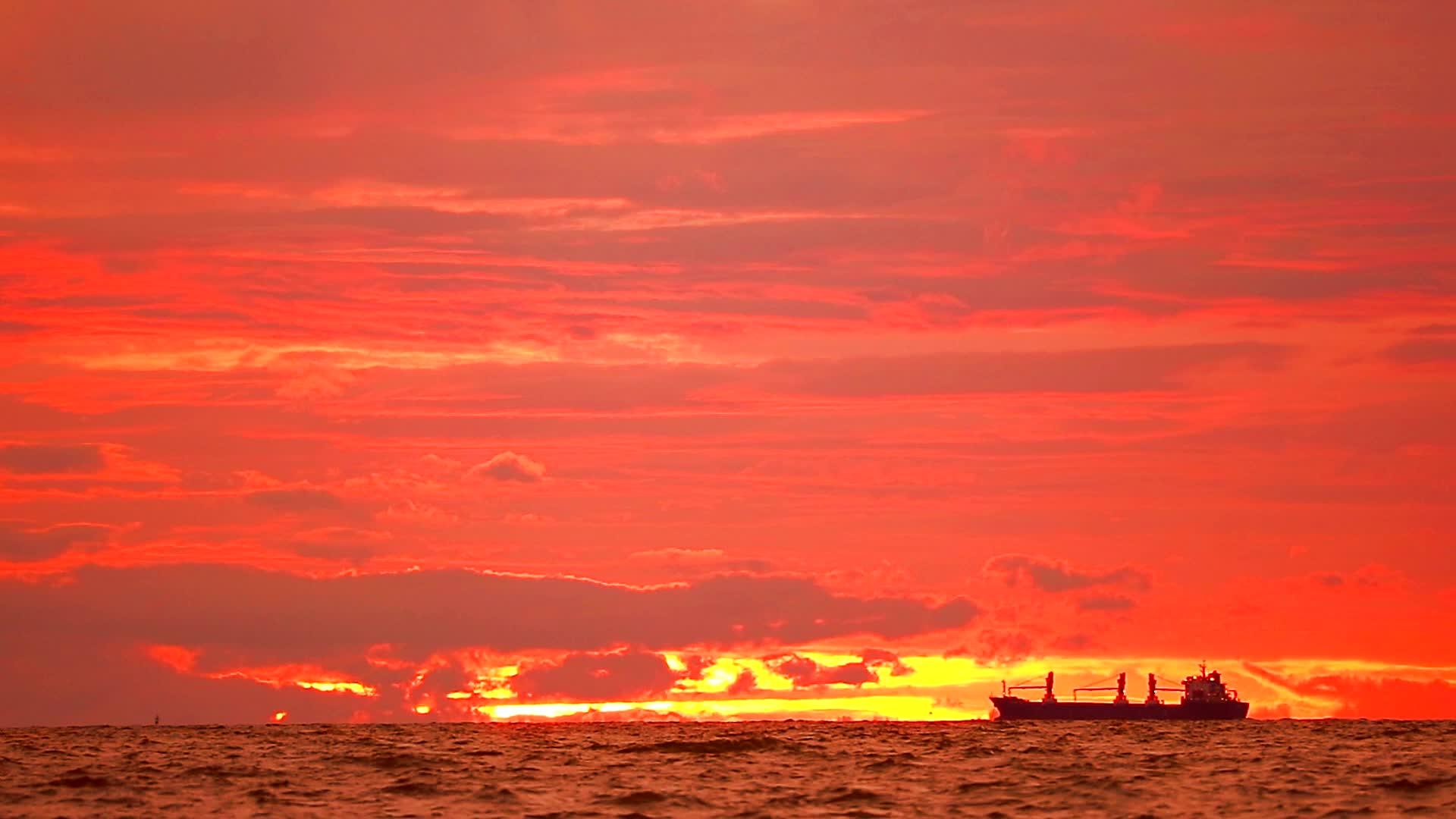 停泊在海上的货船和天空红色的太阳视频的预览图