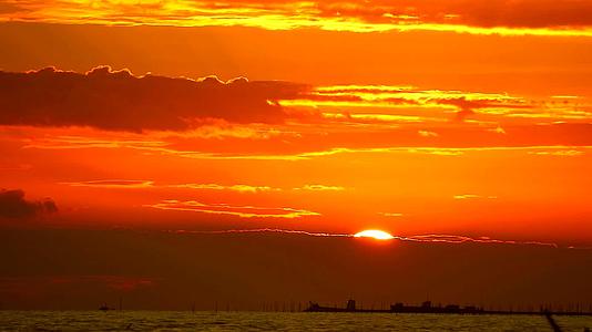 红火日出的橙色天空和海面上的暗红云视频的预览图