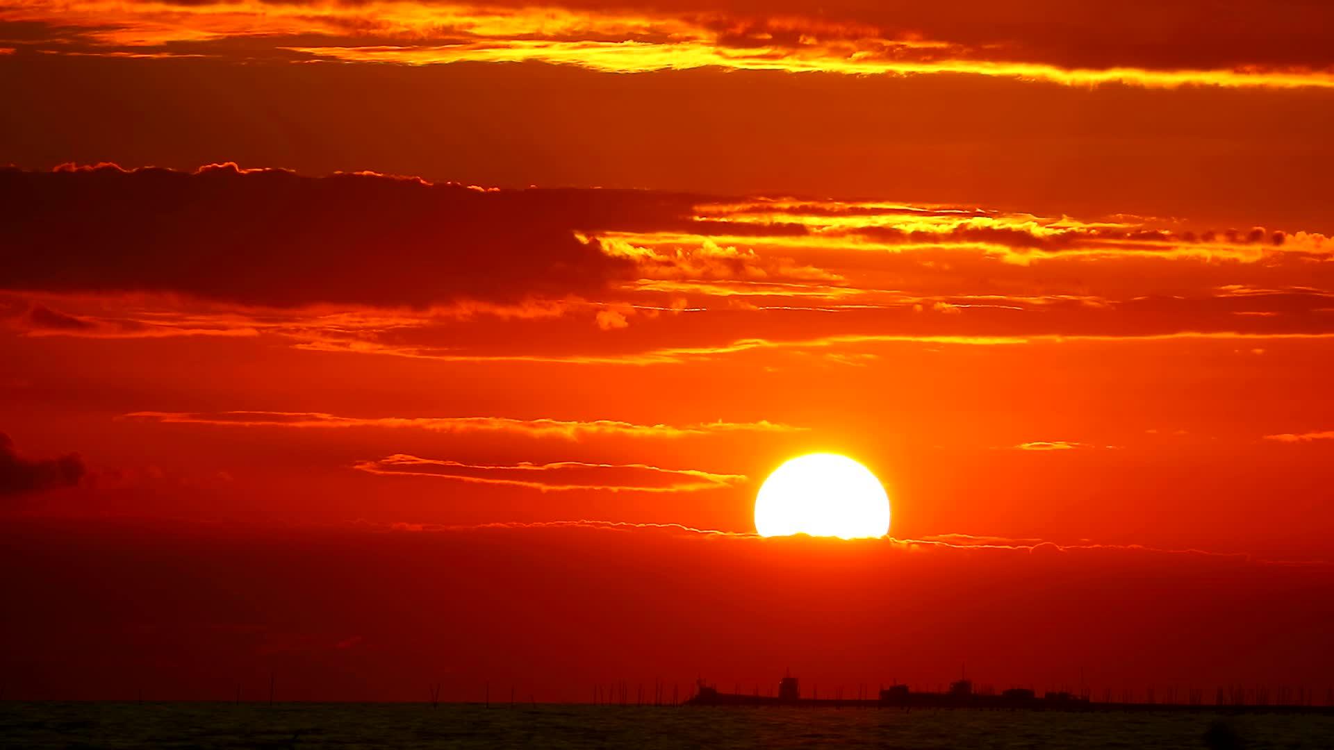 橙色天空中的红色日落和海面上的暗红云视频的预览图
