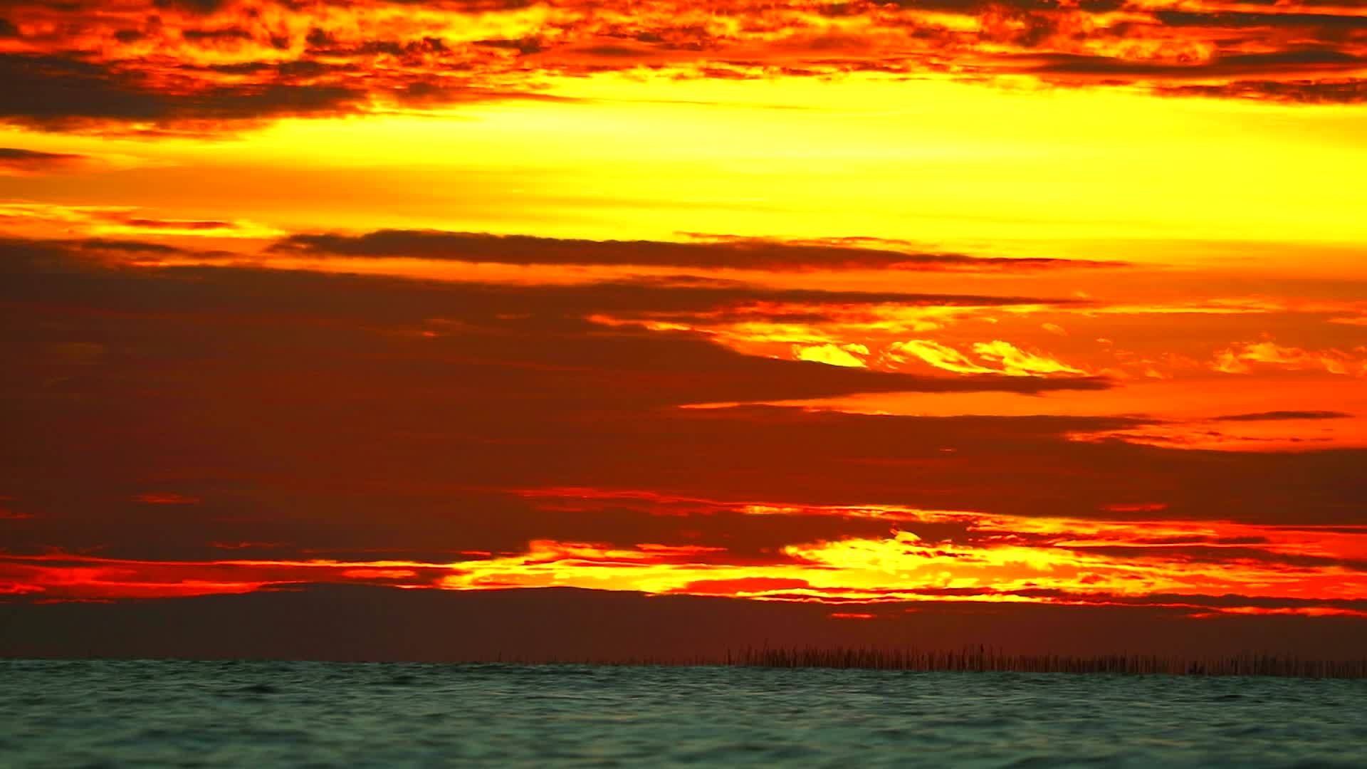 橙色天空中的红色日落和海面上的暗红云视频的预览图