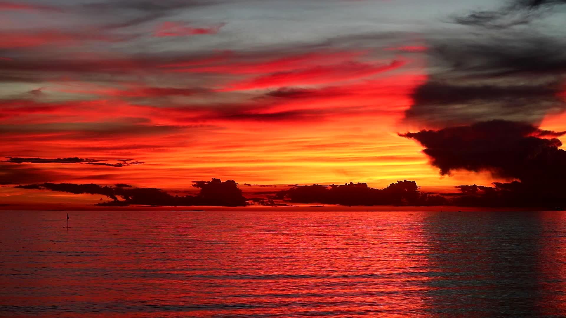 橙色天空的红色日落和海上的黑色和红色月光云视频的预览图