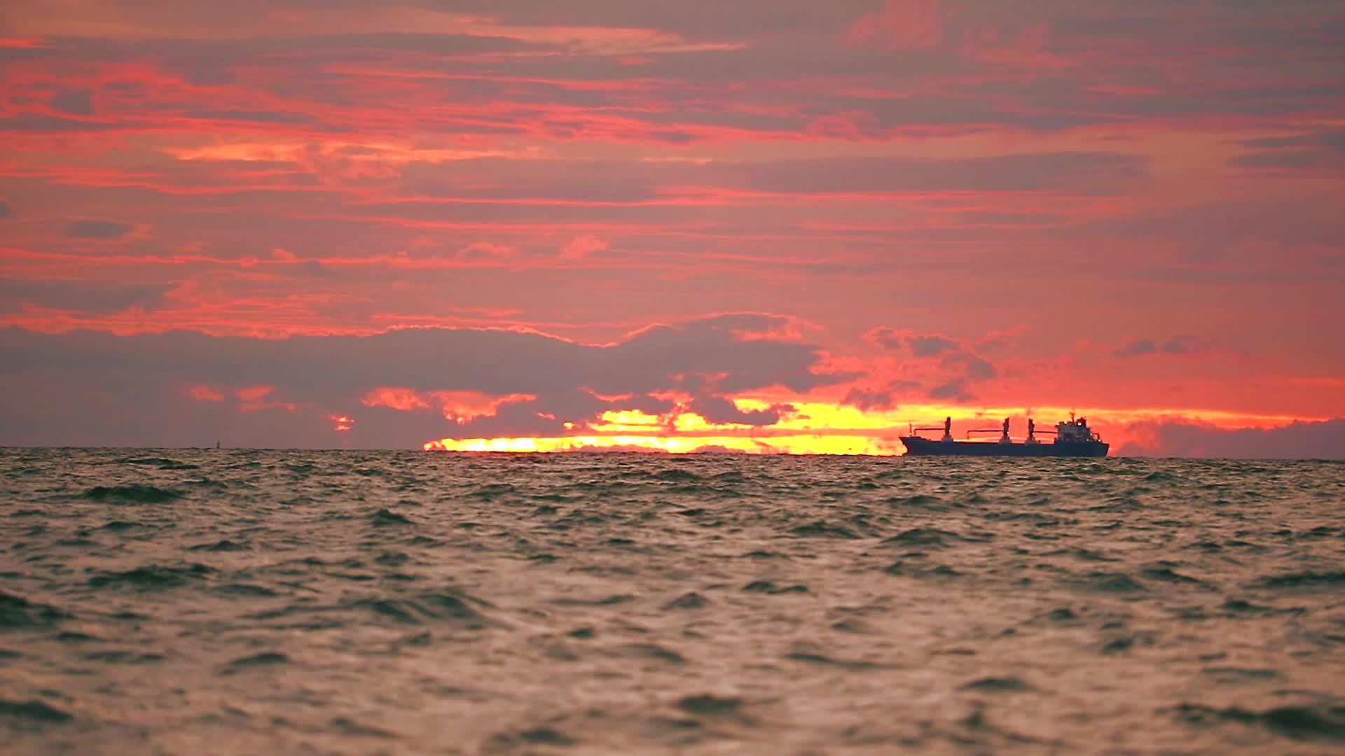 货船停在暗海和日落天空的红云上视频的预览图