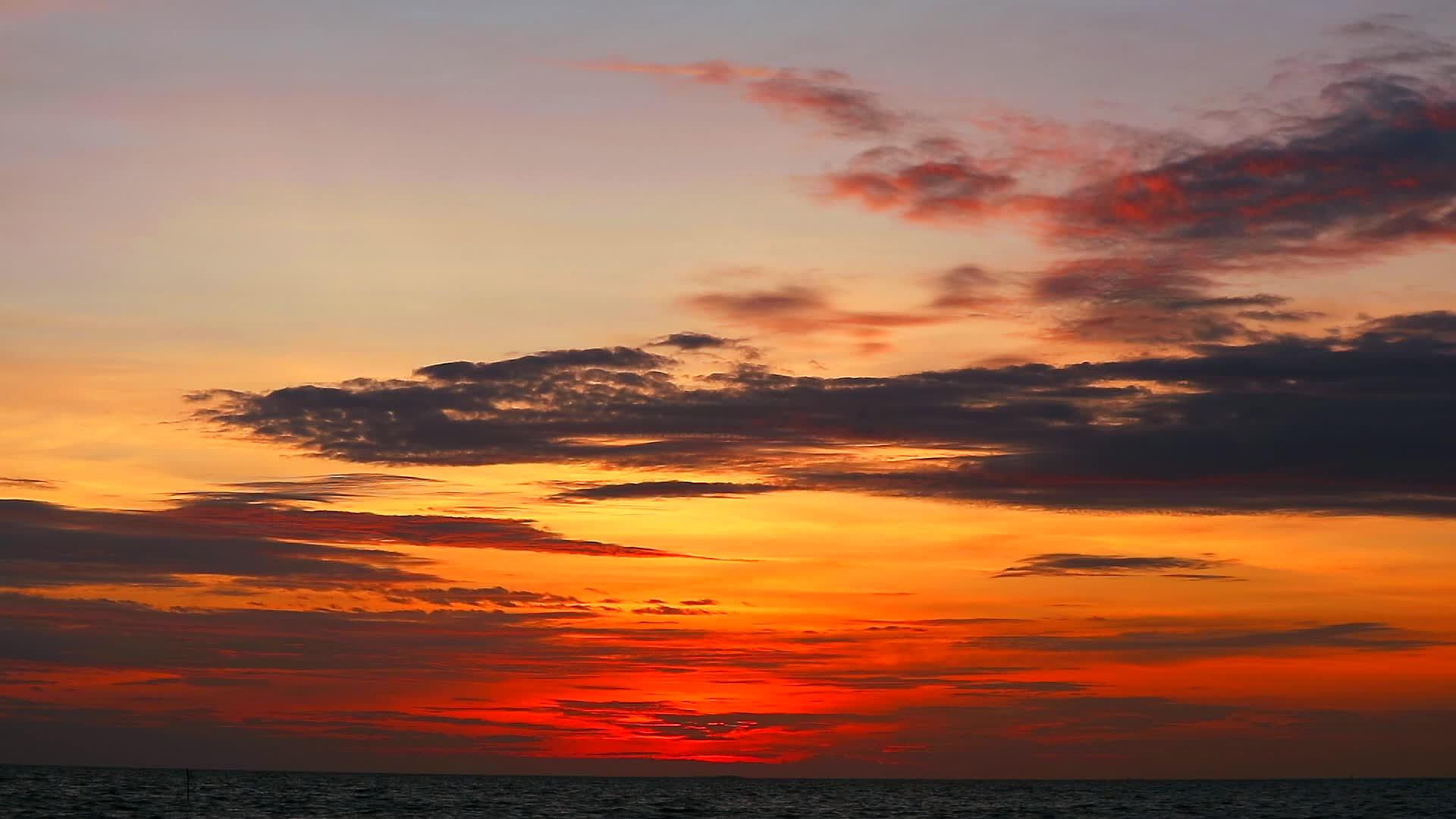 日落、黄色、橙色的天空和深色的红云在海上飘动视频的预览图