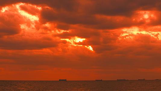日落、黄色、橙色、黄色的天空和红色的风暴云在海上漂浮船只和渔船在航行视频的预览图
