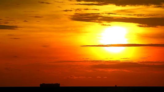 日落、黄色、橙色、黄色的天空和红色的云朵在海上漂浮货船和渔船视频的预览图