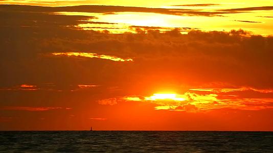 日落橙红色的天空和深红色的云在海上漂浮视频的预览图