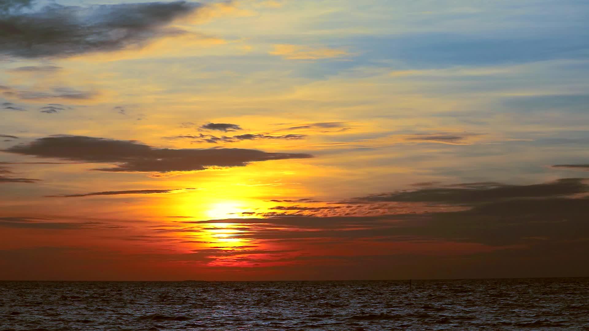 日落橙色的天空和深色的红云在海上移动和波浪视频的预览图